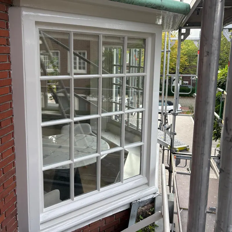 Wit geschilderd kozijn met raamroeden aan de gevel in Amsterdam
